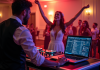 DJ de mariage ajustant un mixer avec mariés dansant en arrière-plan